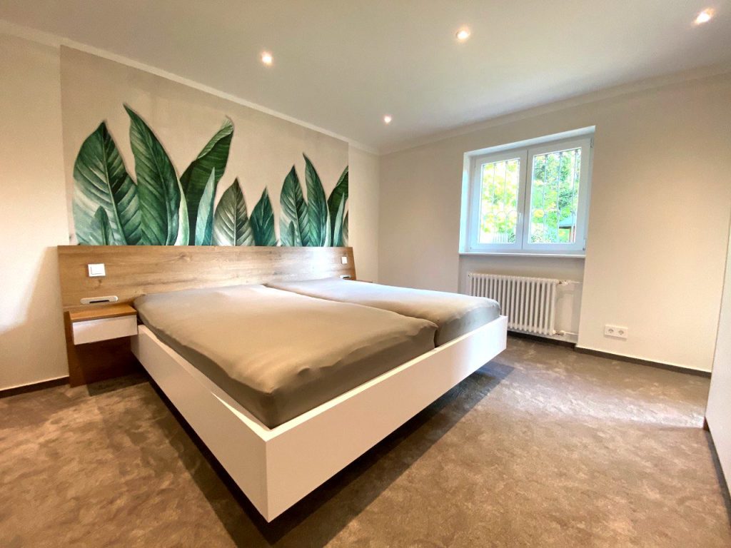 Schlafzimmer mit Kopfteil aus Holz und weißem Bett