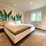Schlafzimmer mit Kopfteil aus Holz und weißem Bett