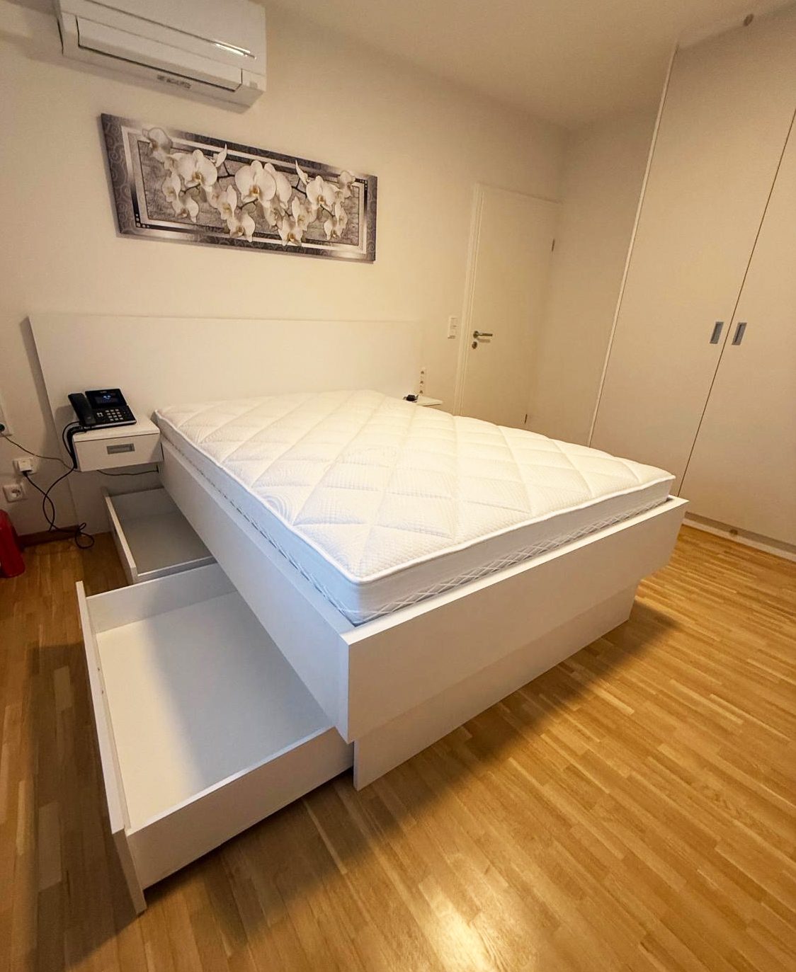 Weißes Bett mit geöffnetem Bettkasten