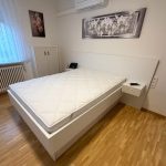 Weißes Bett mit Kopfteil und Nachttischen