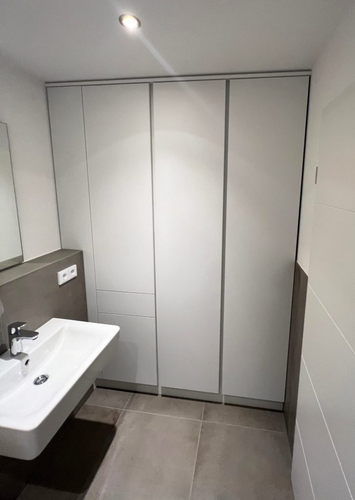 Weißer raumhoher Einbauschrank neben dem Waschbecken
