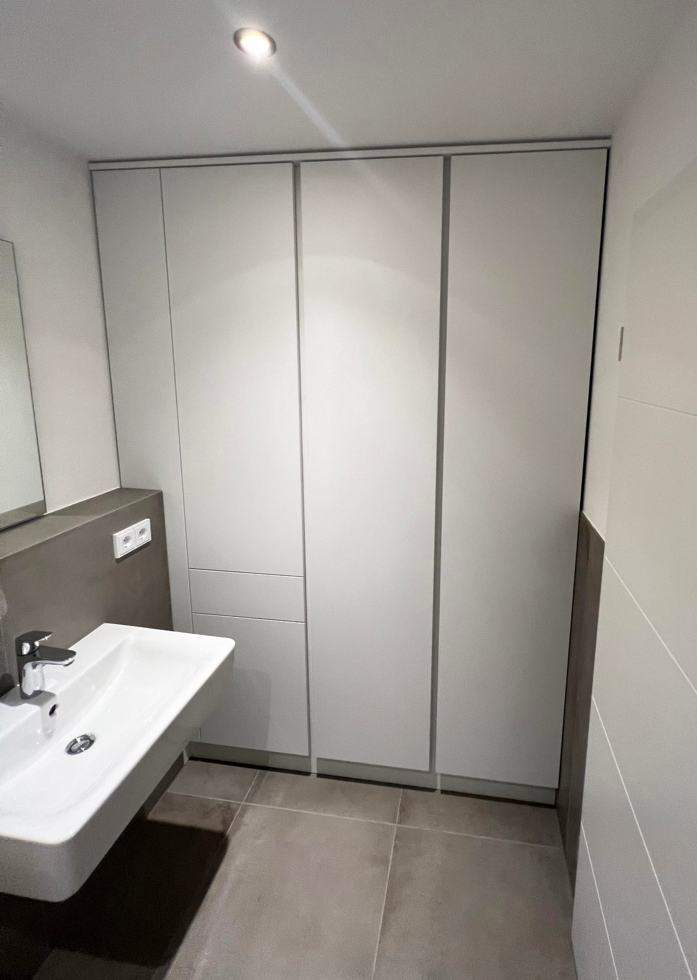 Weißer raumhoher Einbauschrank neben dem Waschbecken