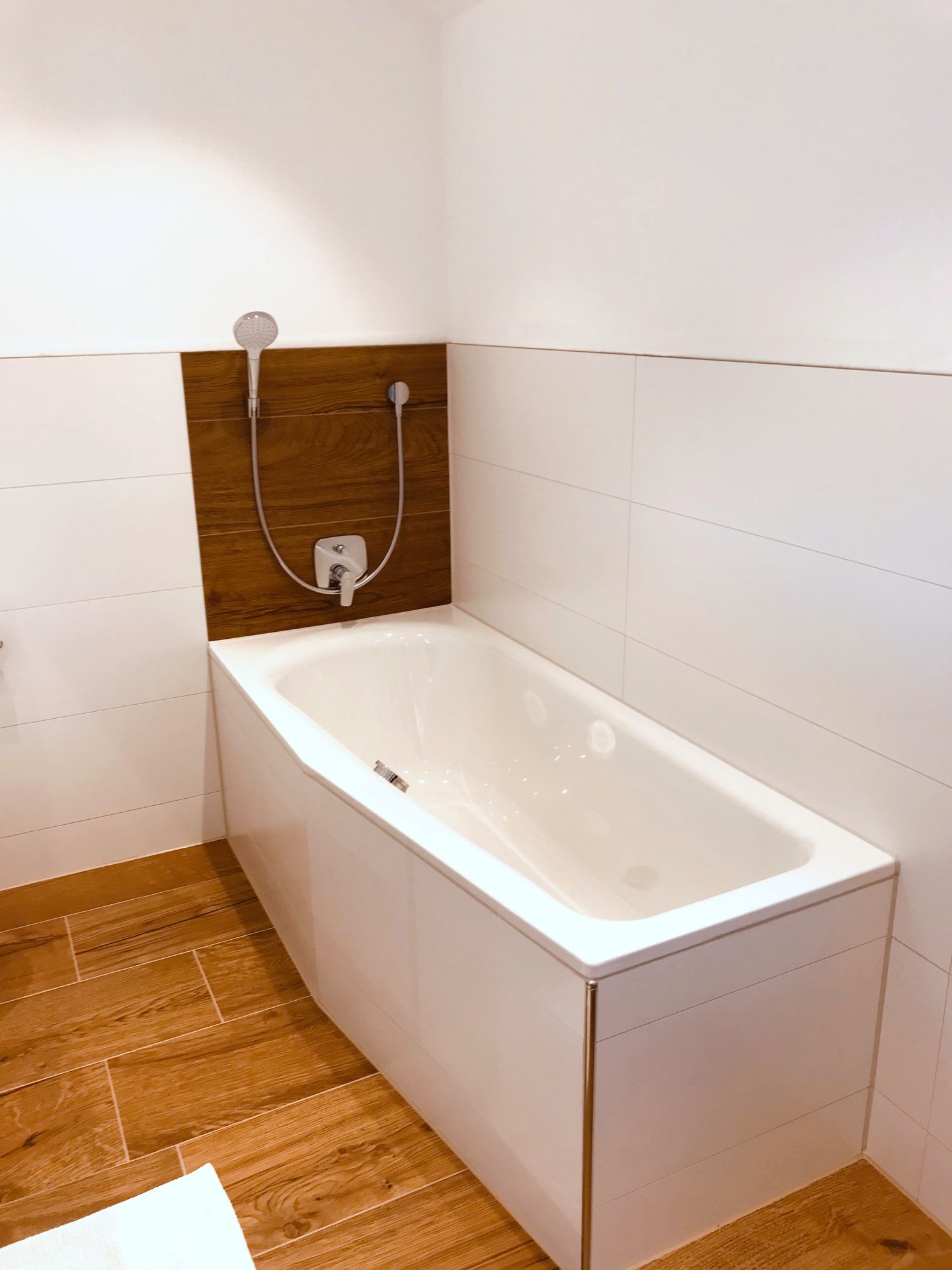 Badewanne vor einer Wand in Holzoptik