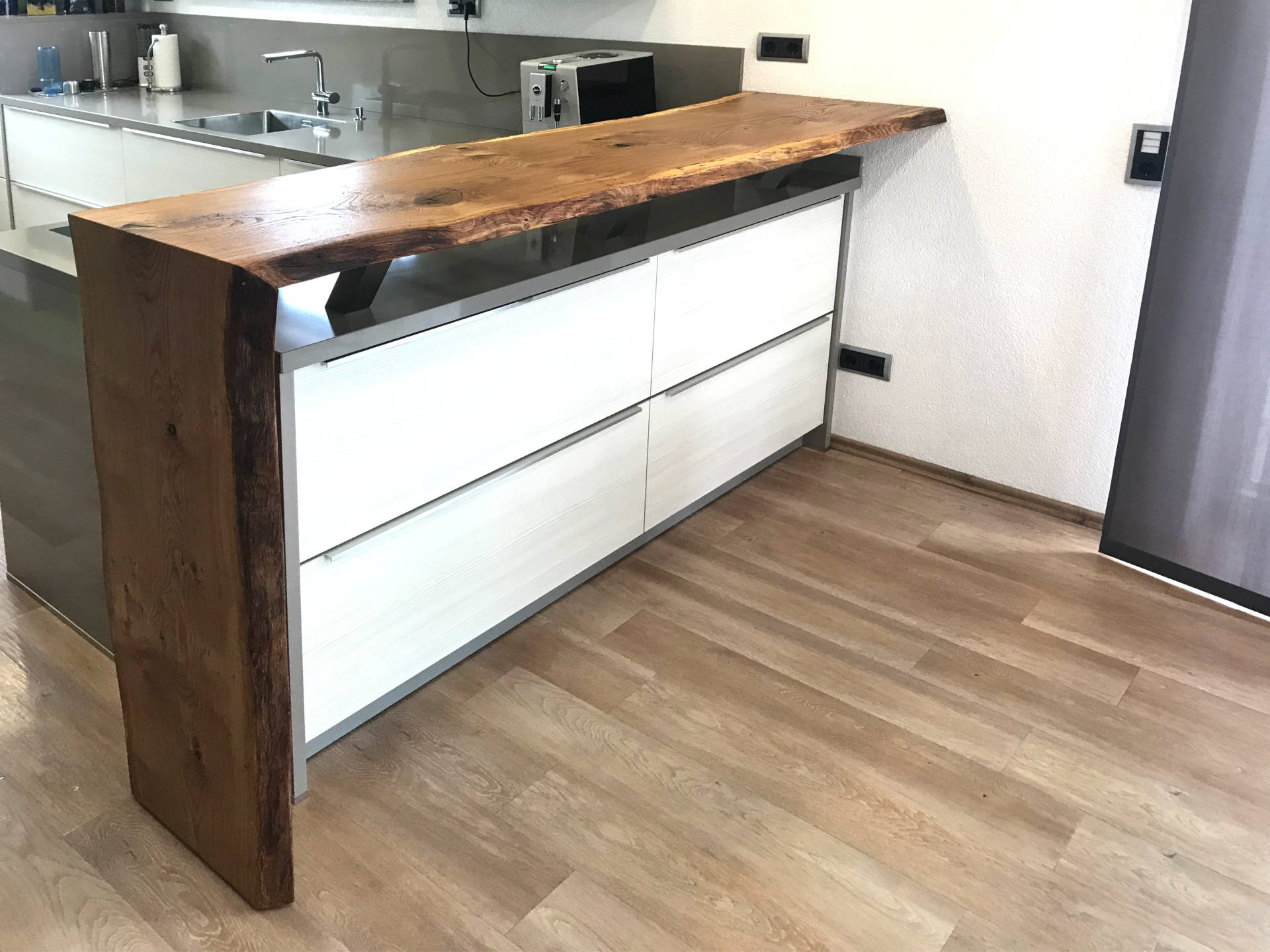 Bartheke aus einer Holzbohle mit Baumkante an der Kücheninsel