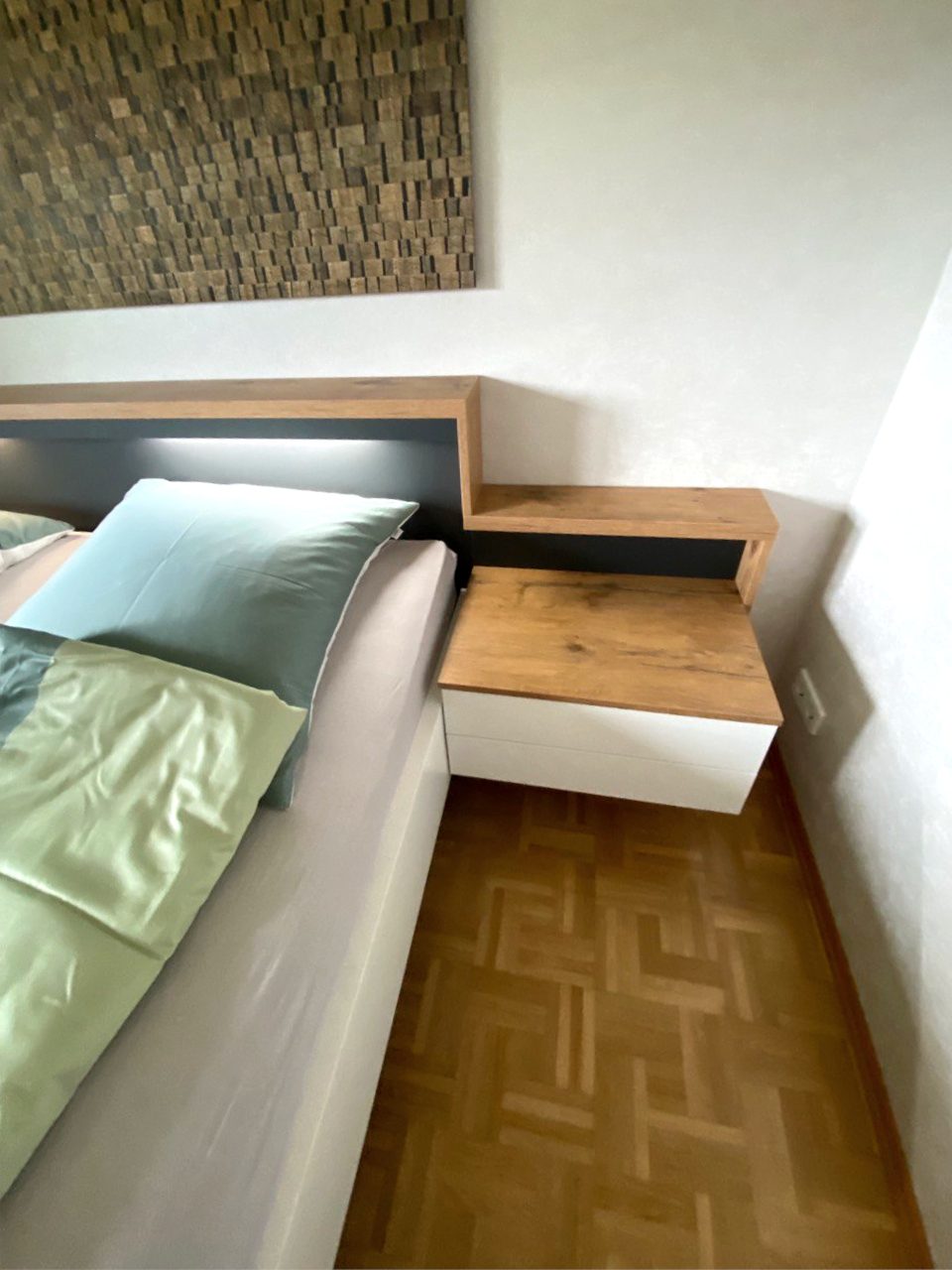 Nachttisch mit Platte in Holzoptik neben dem Bett