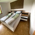 Bett mit beleuchtetem Kopfteil und geöffneter Schublade