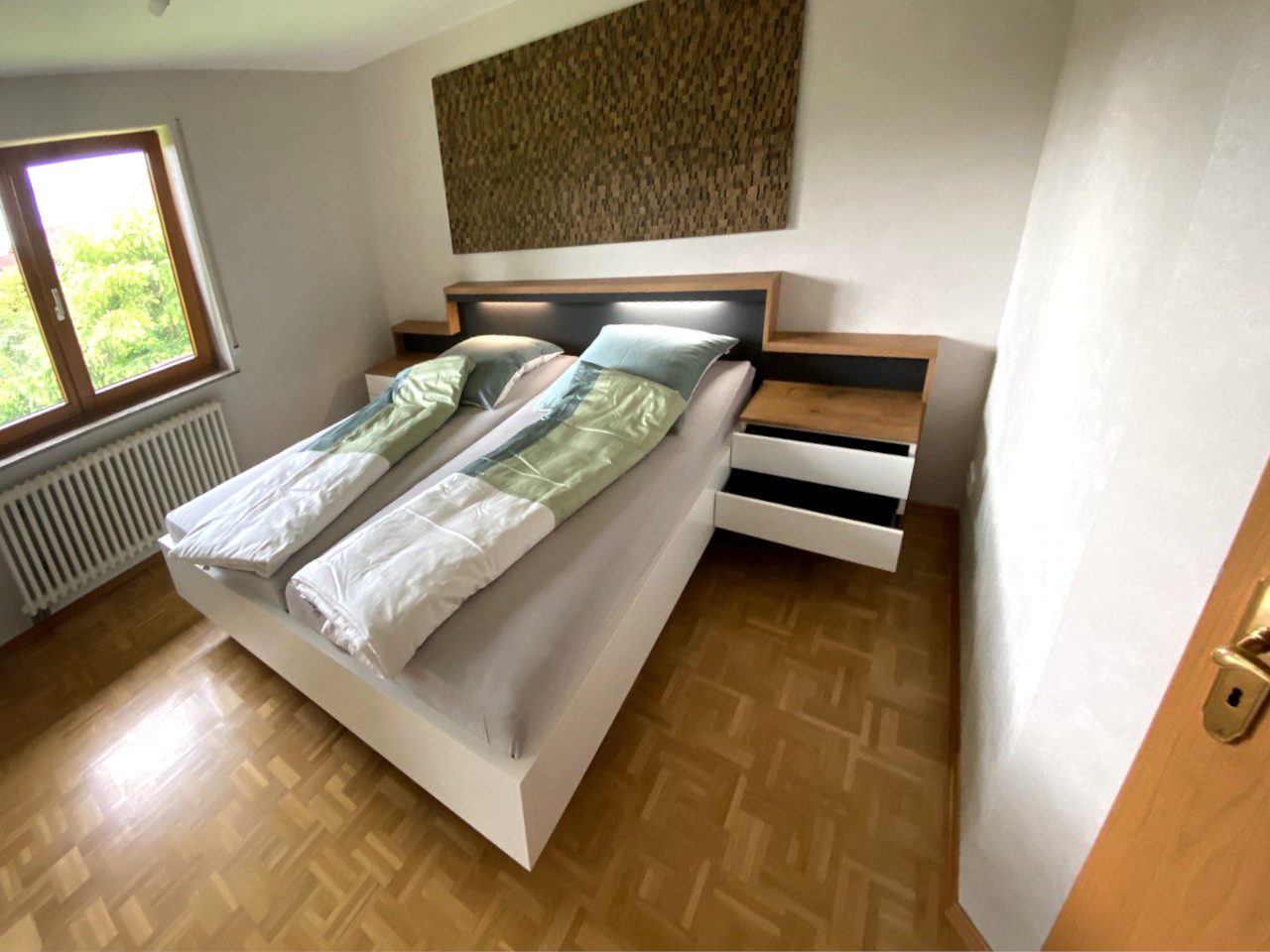 Bett mit beleuchtetem Kopfteil und geöffneter Schublade