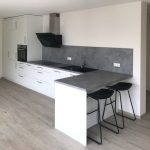 Lange weiße Küche mit Theke und Barhockern