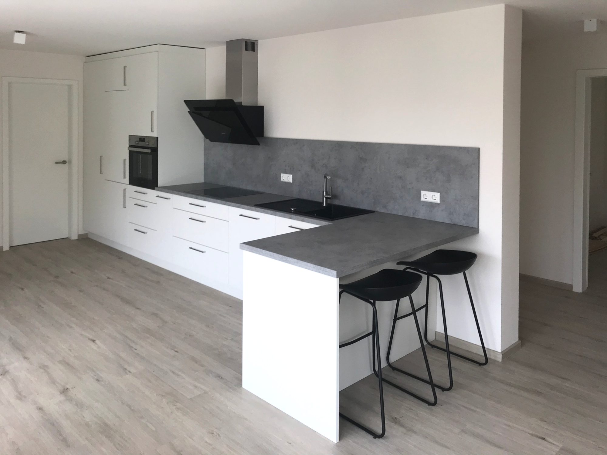 Lange weiße Küche mit Theke und Barhockern