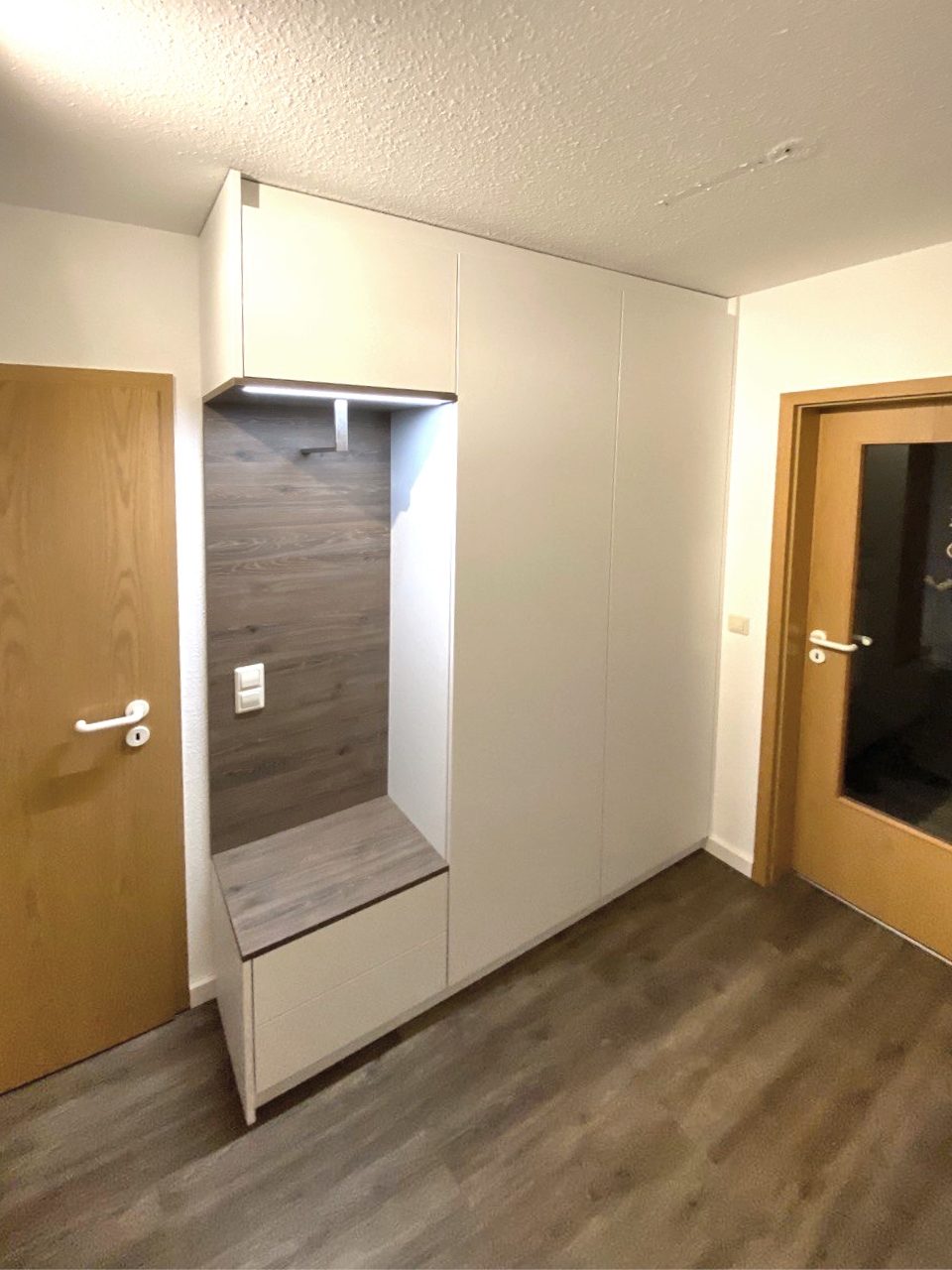 Garderobe mit dunkler Wandplatte und Sitzbank