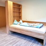 Einzelbett mit hohem Regal als Kopfteil