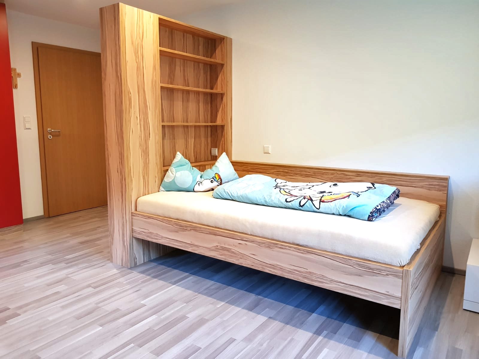 Einzelbett mit hohem Regal als Kopfteil