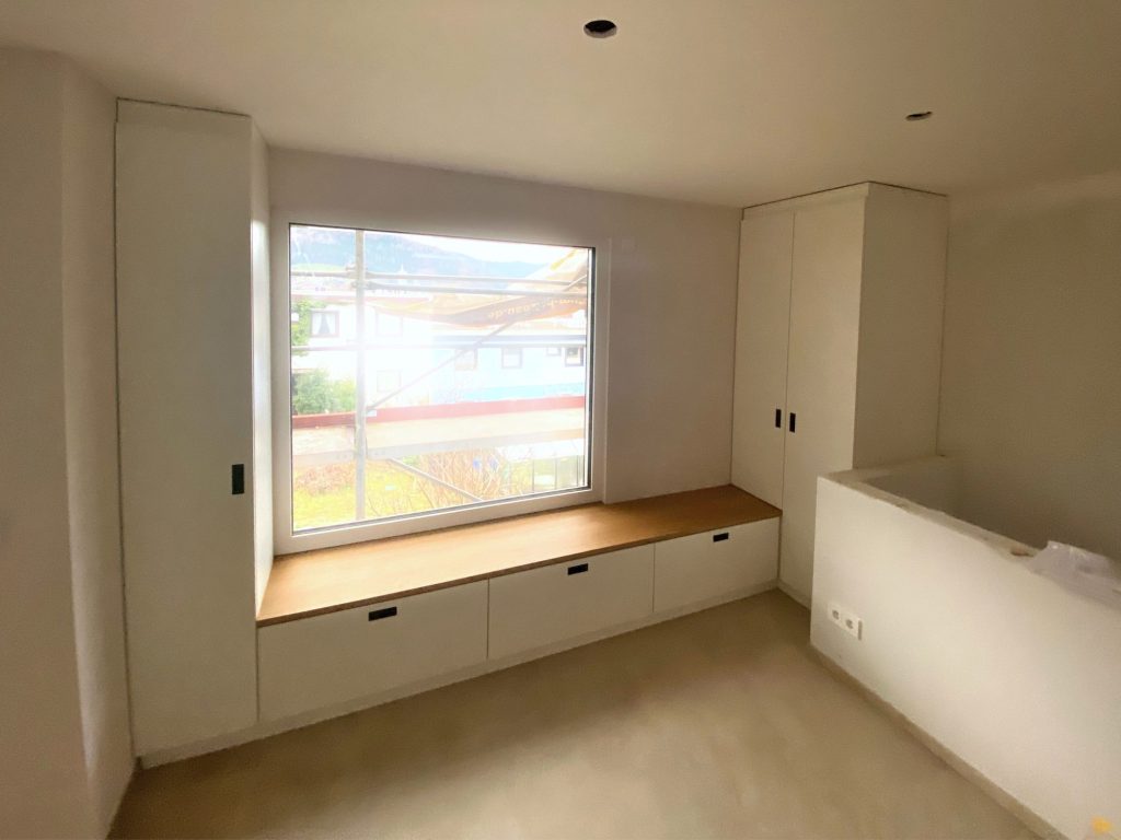 Fenstersitzbank zwischen weißen Hochschränken