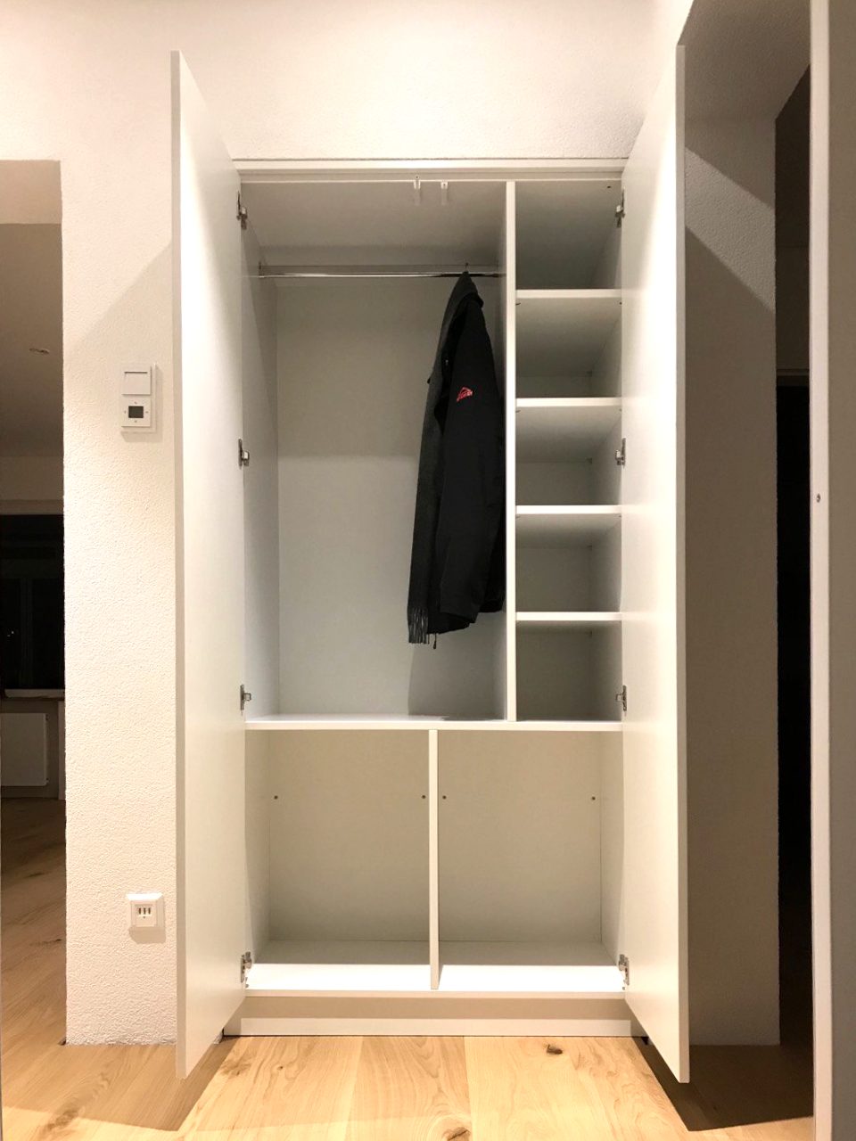 Geöffneter Schrank mit Kleiderstange und Fächern