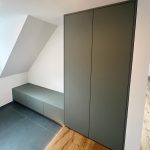 Graugrüner Hochschrank und niedrige Bank unter der Dachschräge