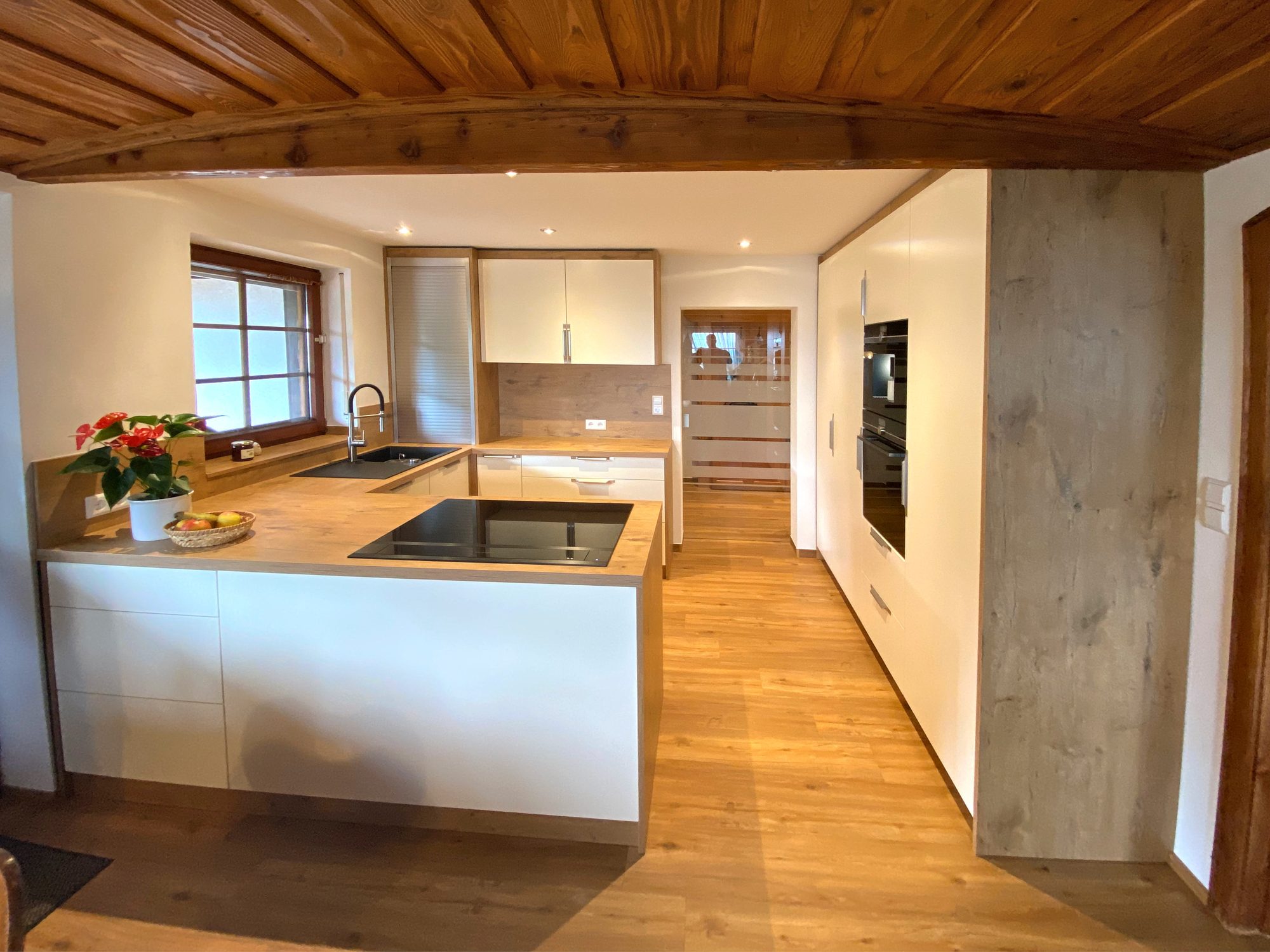 Helle Küche mit Halbinsel unter einer Holzdecke