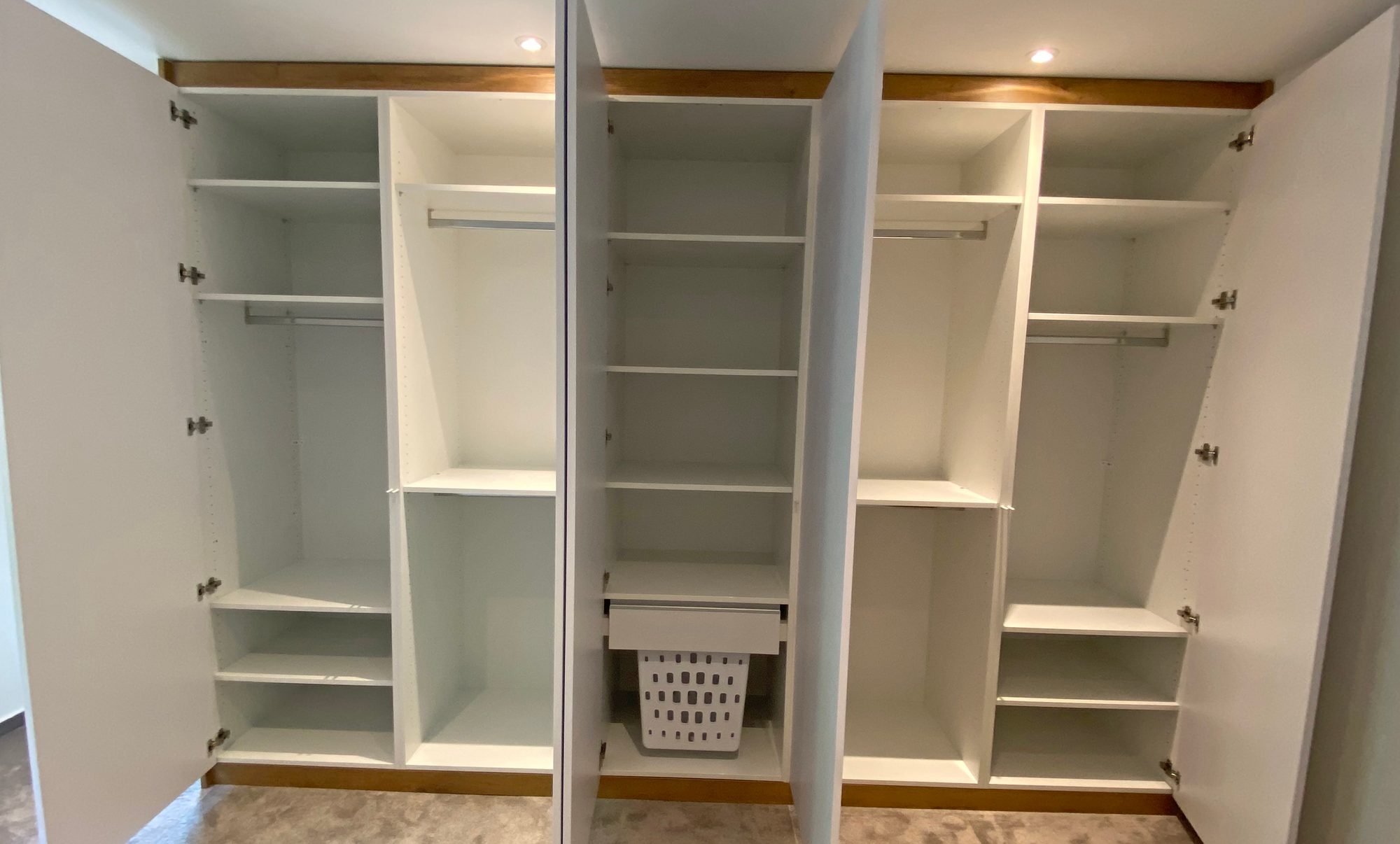 Geöffneter Kleiderschrank mit Fachböden und Kleiderstangen
