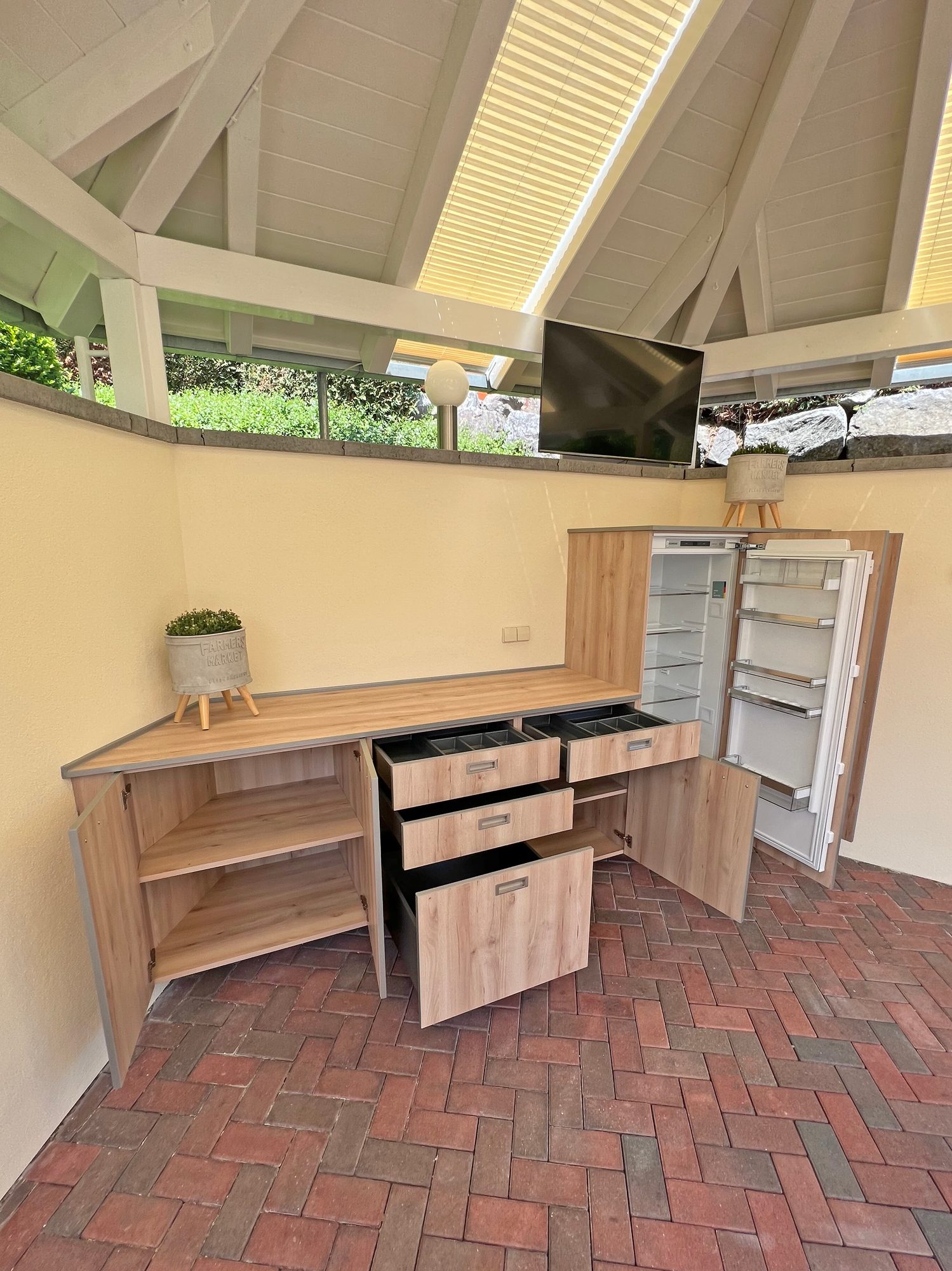 Küchenzeile mit geöffneten Schubkästen und Kühlschrank im Pavillon