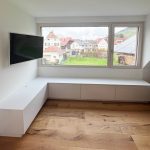 Weißes Lowboard über Eck unter dem Fenster