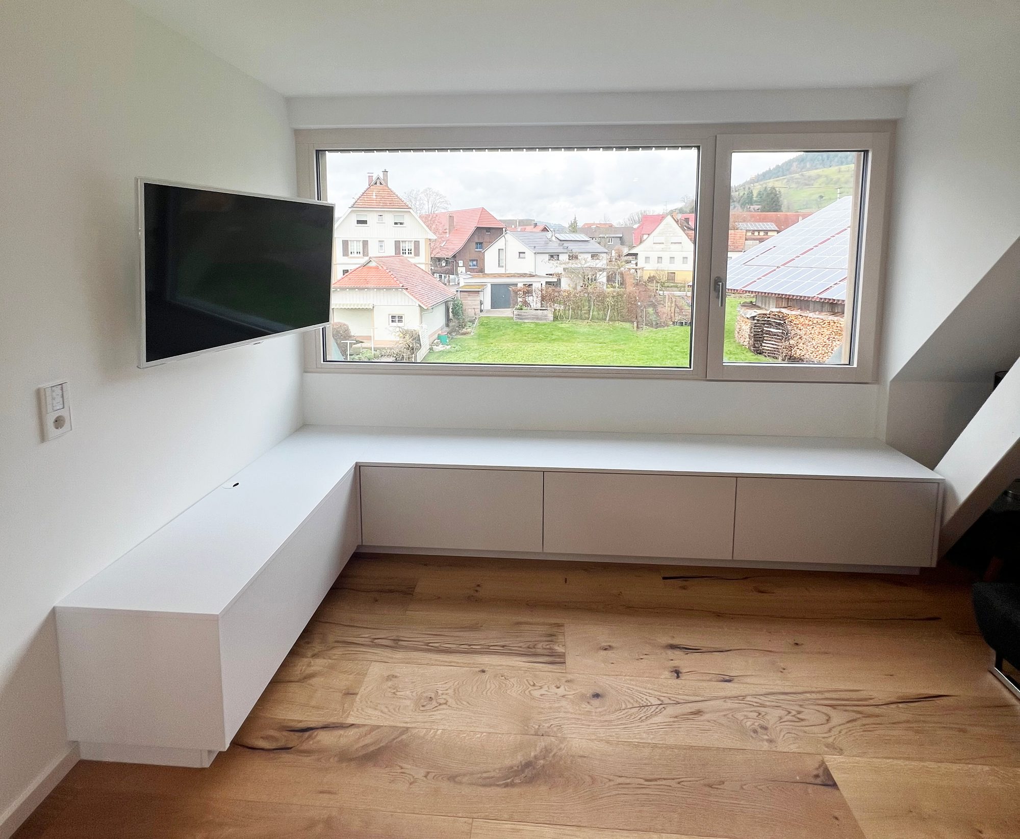 Weißes Lowboard über Eck unter dem Fenster