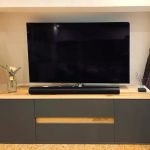 Anthrazitfarbenes Lowboard mit Holzplatte unter dem Fernseher