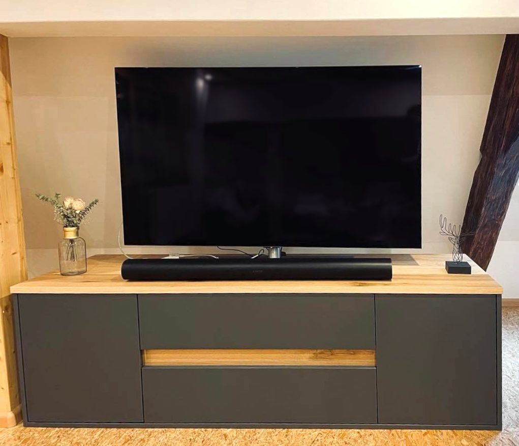 Anthrazitfarbenes Lowboard mit Holzplatte unter dem Fernseher