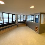 Sitzbank unter der Fensterfront mit Fächern
