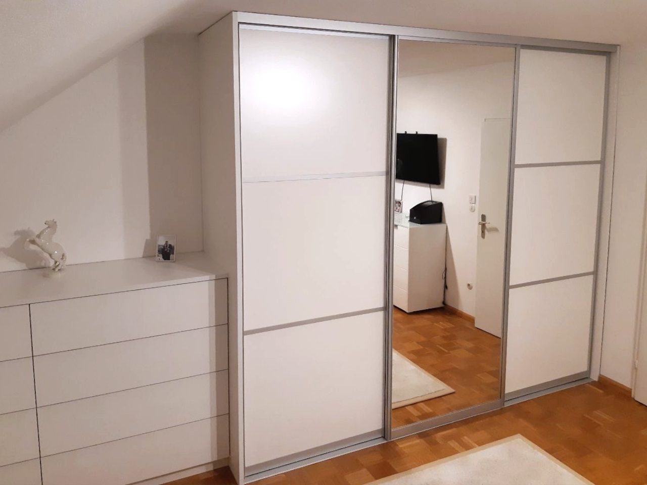 Schwebetürenschrank mit Spiegeltür neben einer Kommode