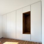 Weiße Schrankwand unter der Dachschräge mit Nische in Holzoptik