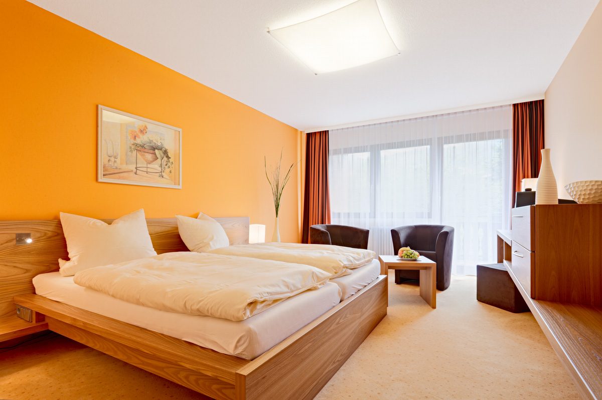 Schlafzimmer mit Doppelbett in Holzoptik und passenden Möbeln