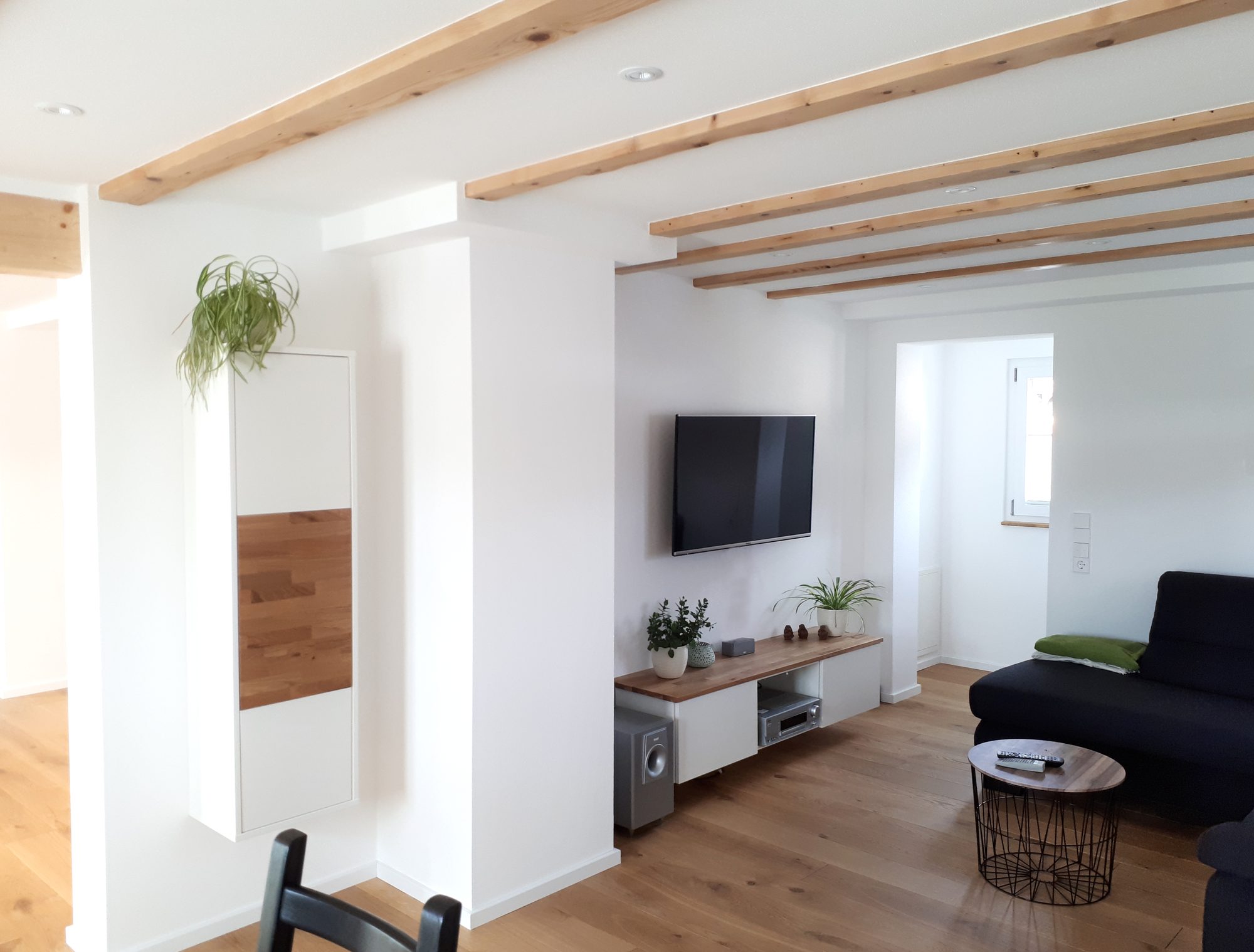 Wohnzimmer mit Hängeschrank und Lowboard unter Holzbalken