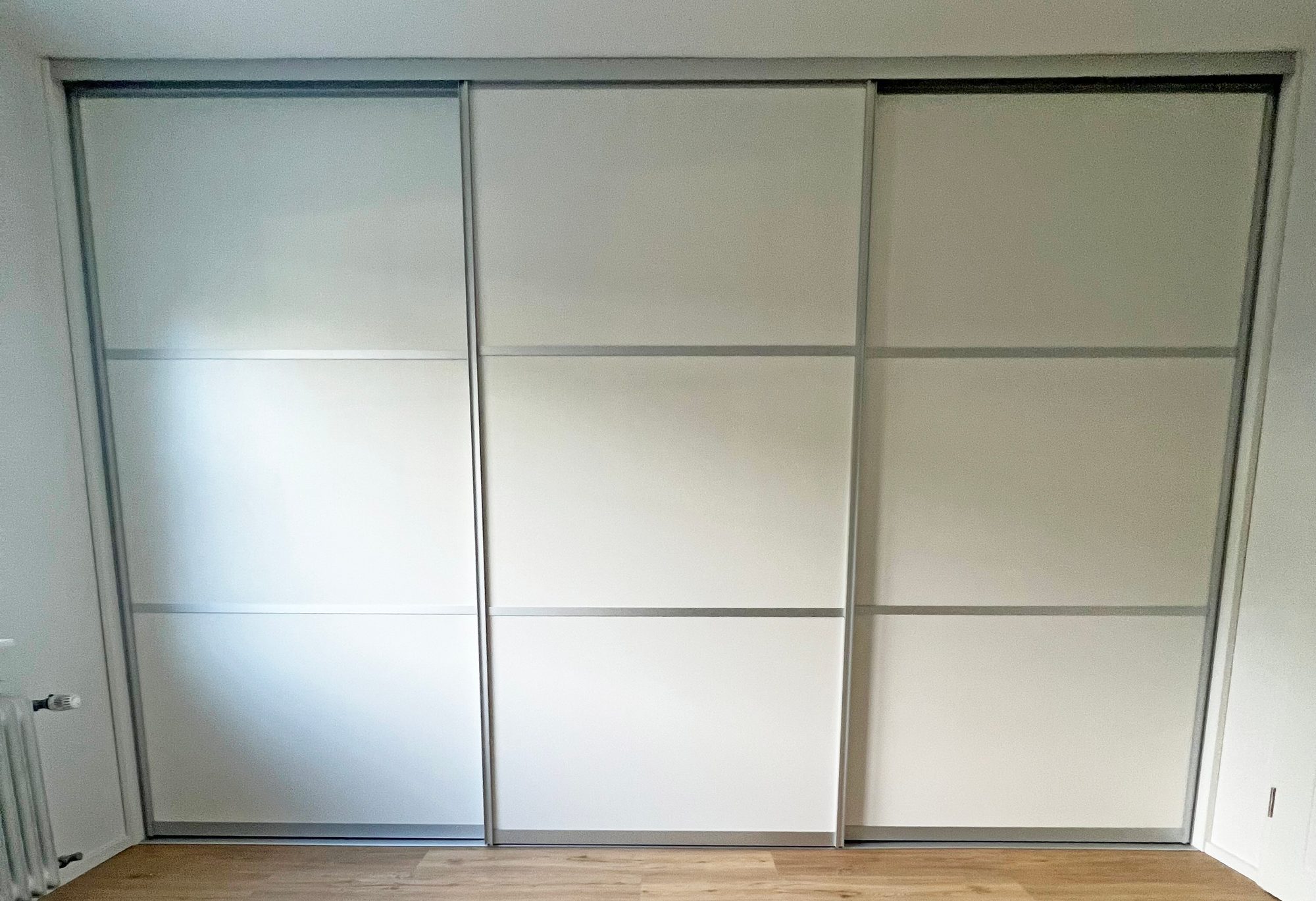 Geschlossener weißer Schwebetürenschrank