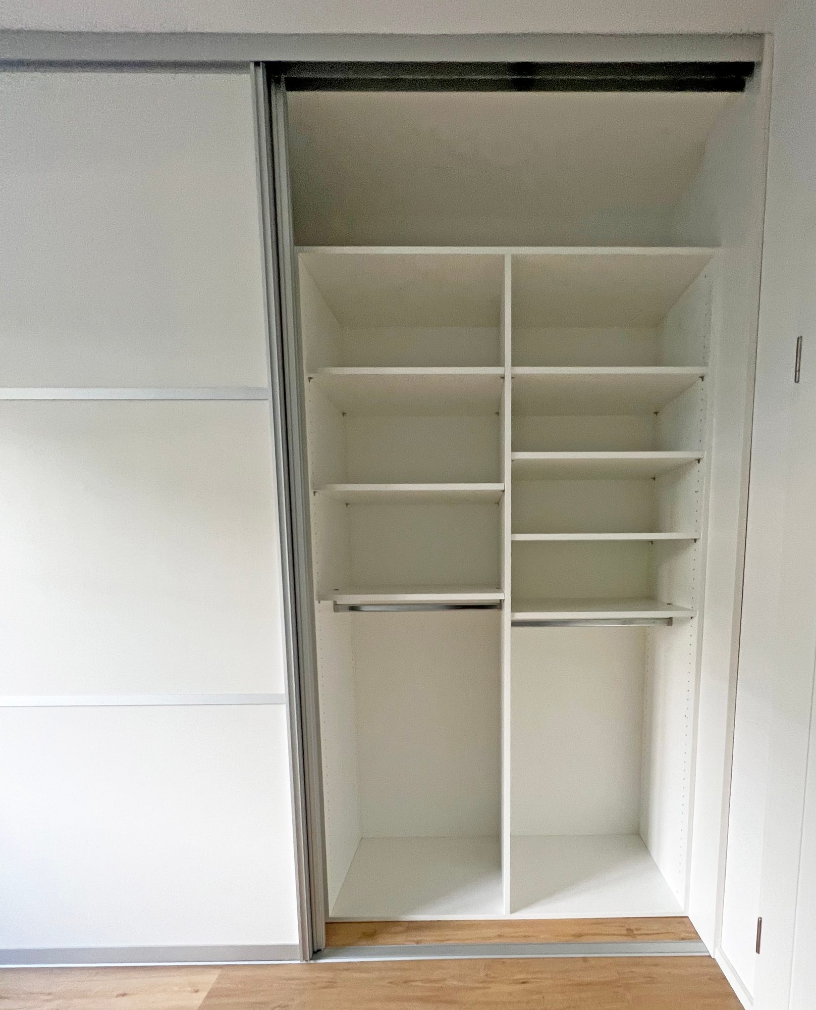 Geöffneter Schrank mit Fachböden und Kleiderstange
