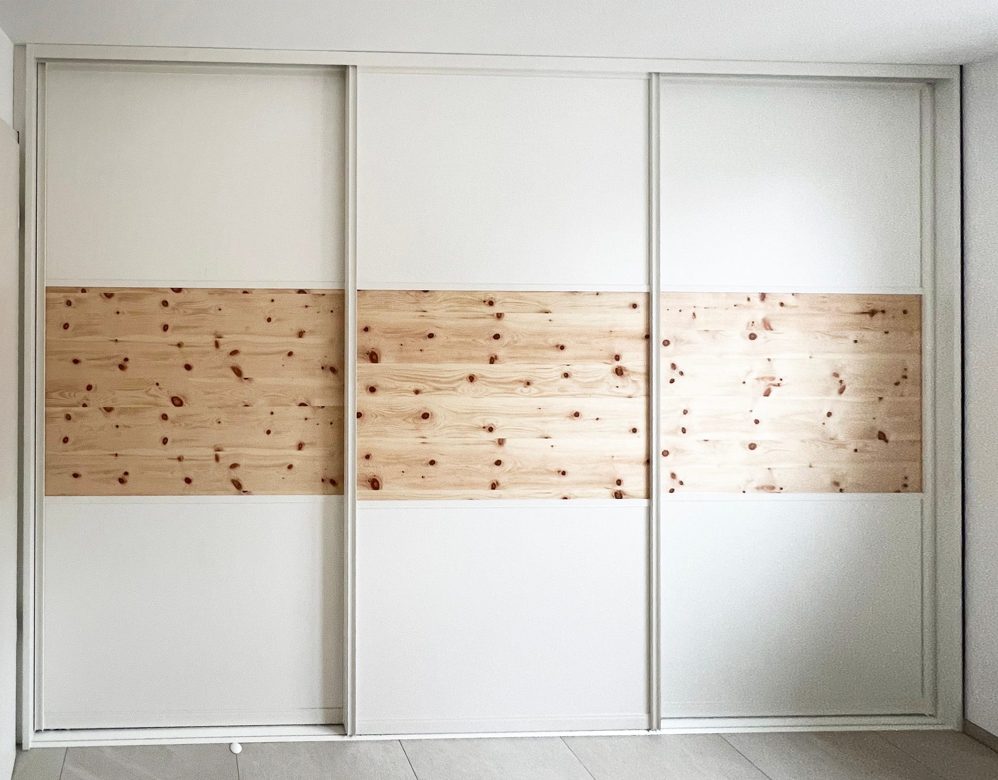 Weißer Schwebetürenschrank mit durchgehendem Holzband