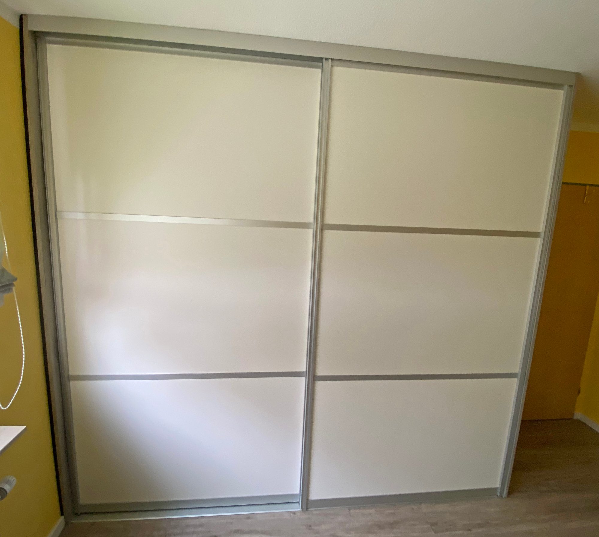 Geschlossener weißer Schwebetürenschrank mit Aluminiumrahmen