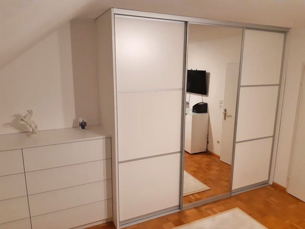 Schwebetürenschrank mit Spiegeltür neben einer Kommode