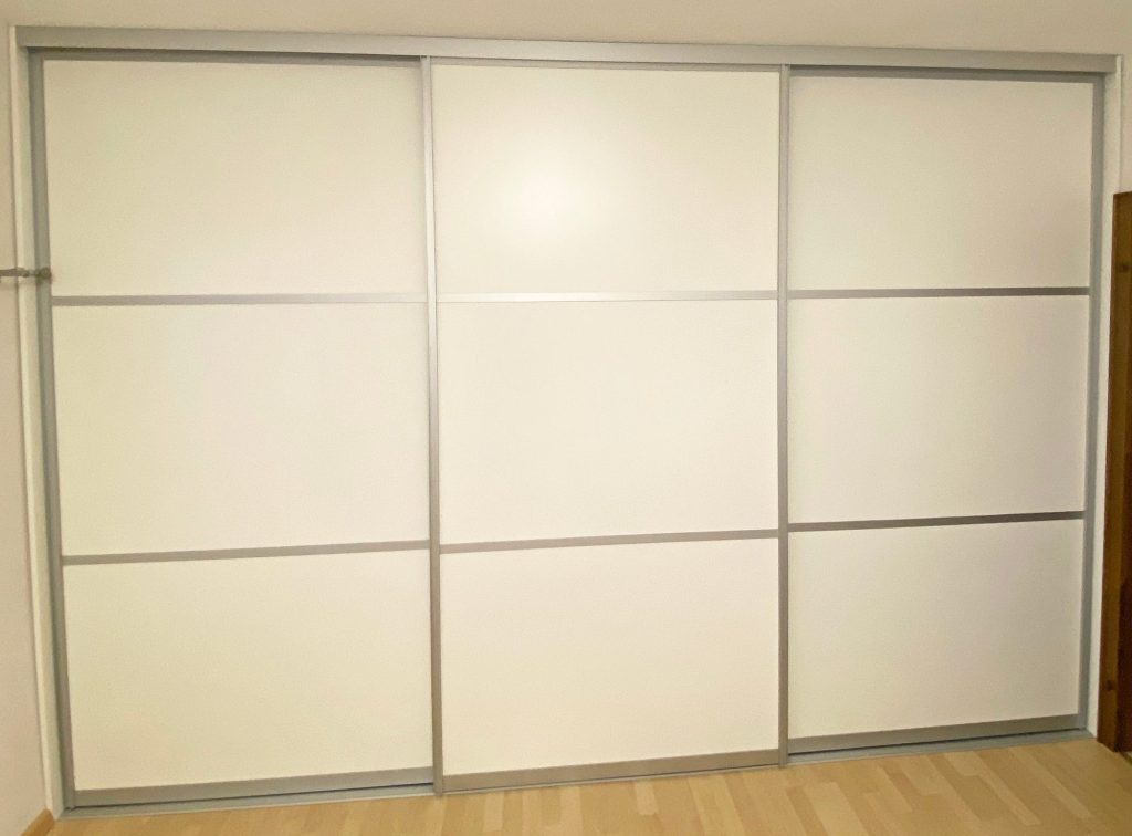 Geschlossener weißer Schwebetürenschrank