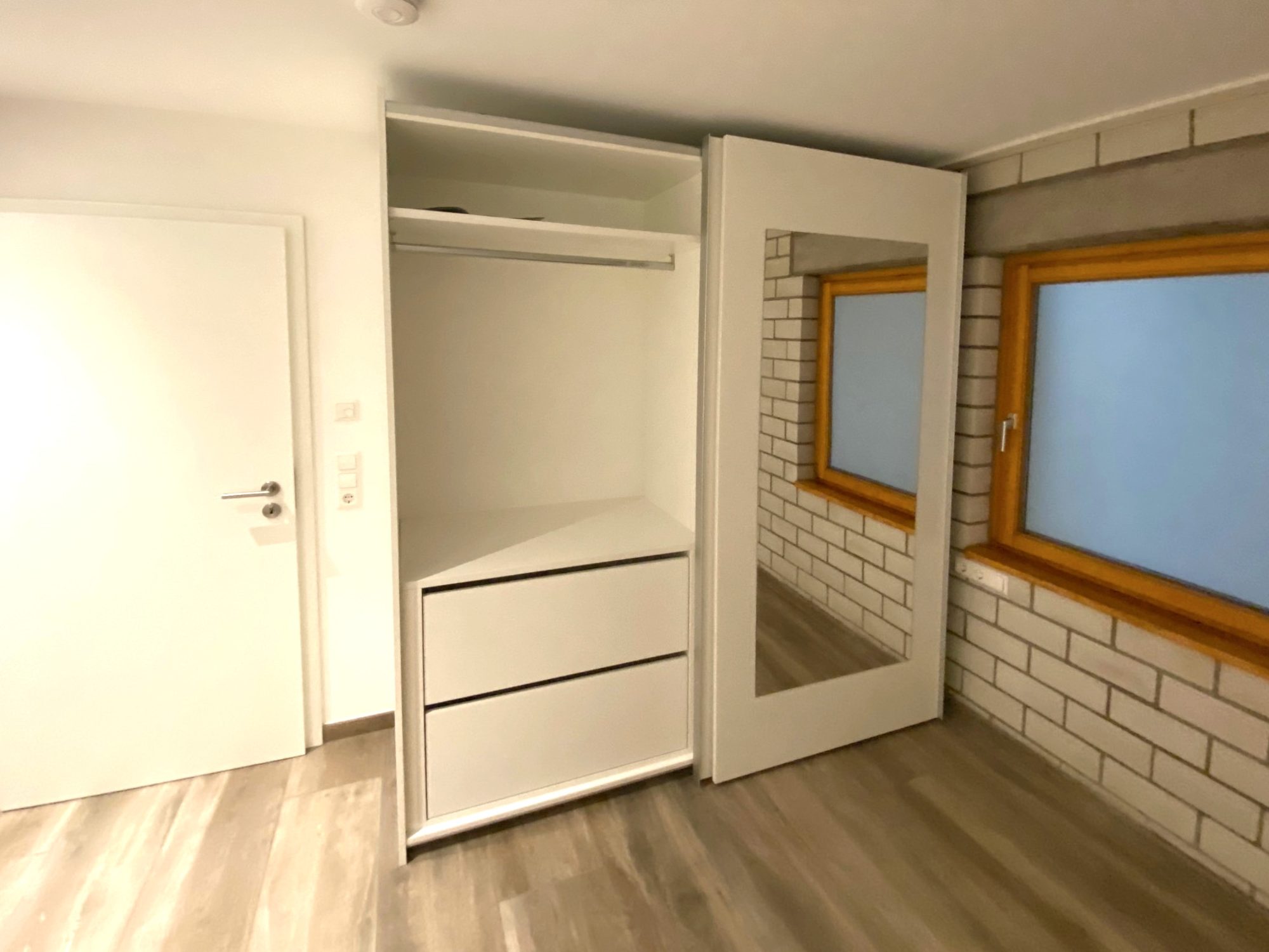 Geöffneter Spiegelschrank mit Kleiderstange und Schubkästen