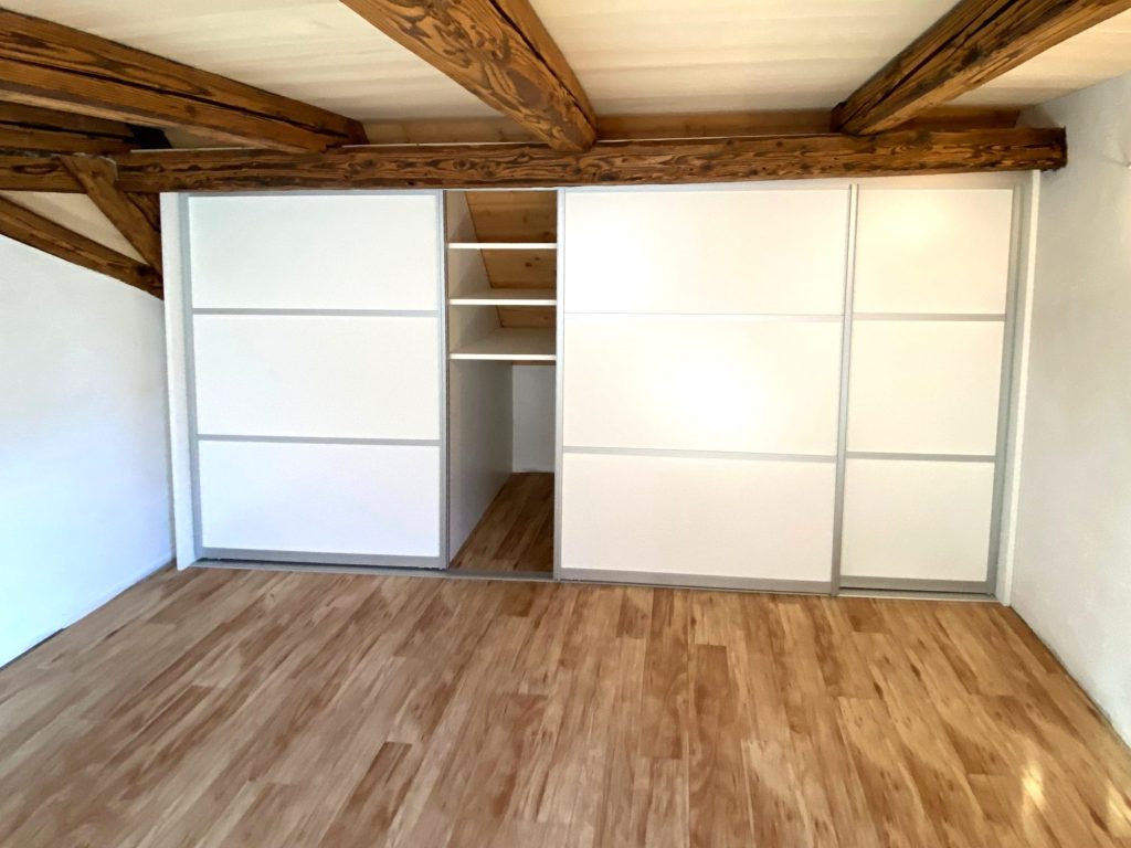 Schwebetürenschrank unter alten Holzbalken