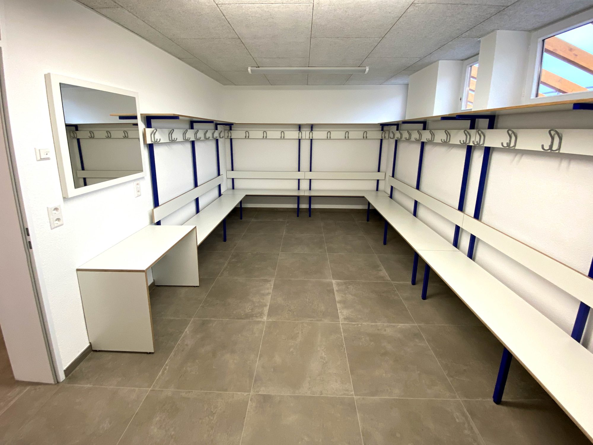 Umkleide mit Sitzbänken und Hakenleisten an allen Wänden