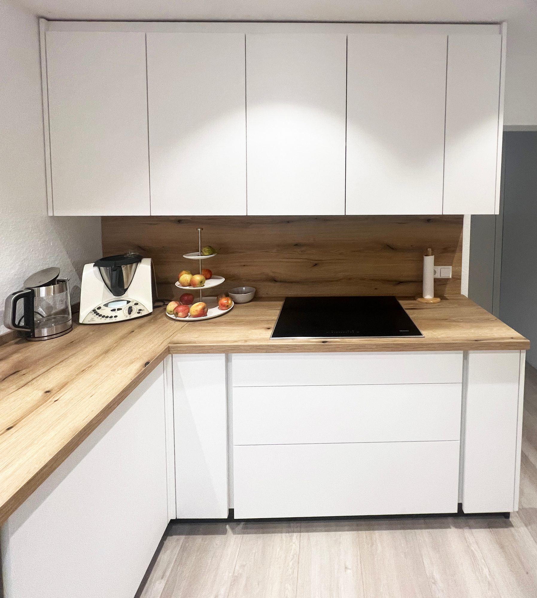 Kochfeld mit breiten Schubkästen und Rückwand in Holzoptik