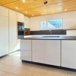 Weiße Küche mit freistehender Insel und dunkler Arbeitsplatte