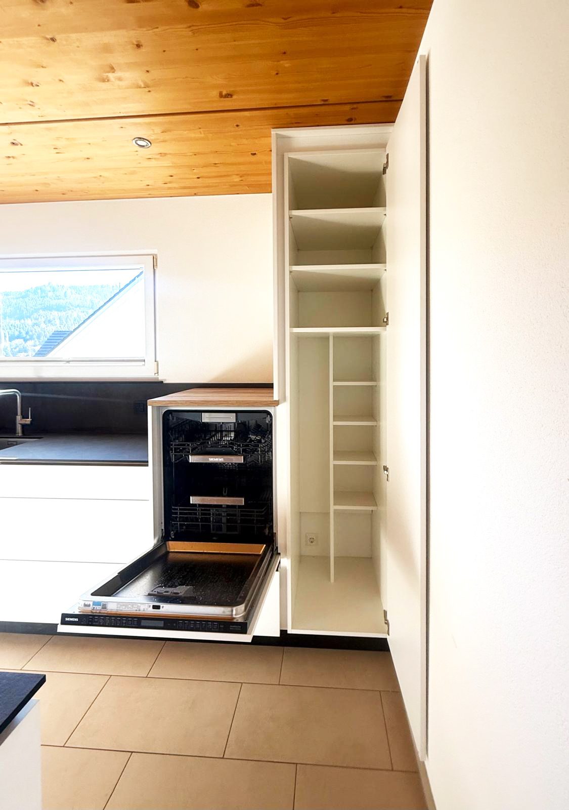 Geöffneter Hochschrank mit Regalböden neben dem Geschirrspüler