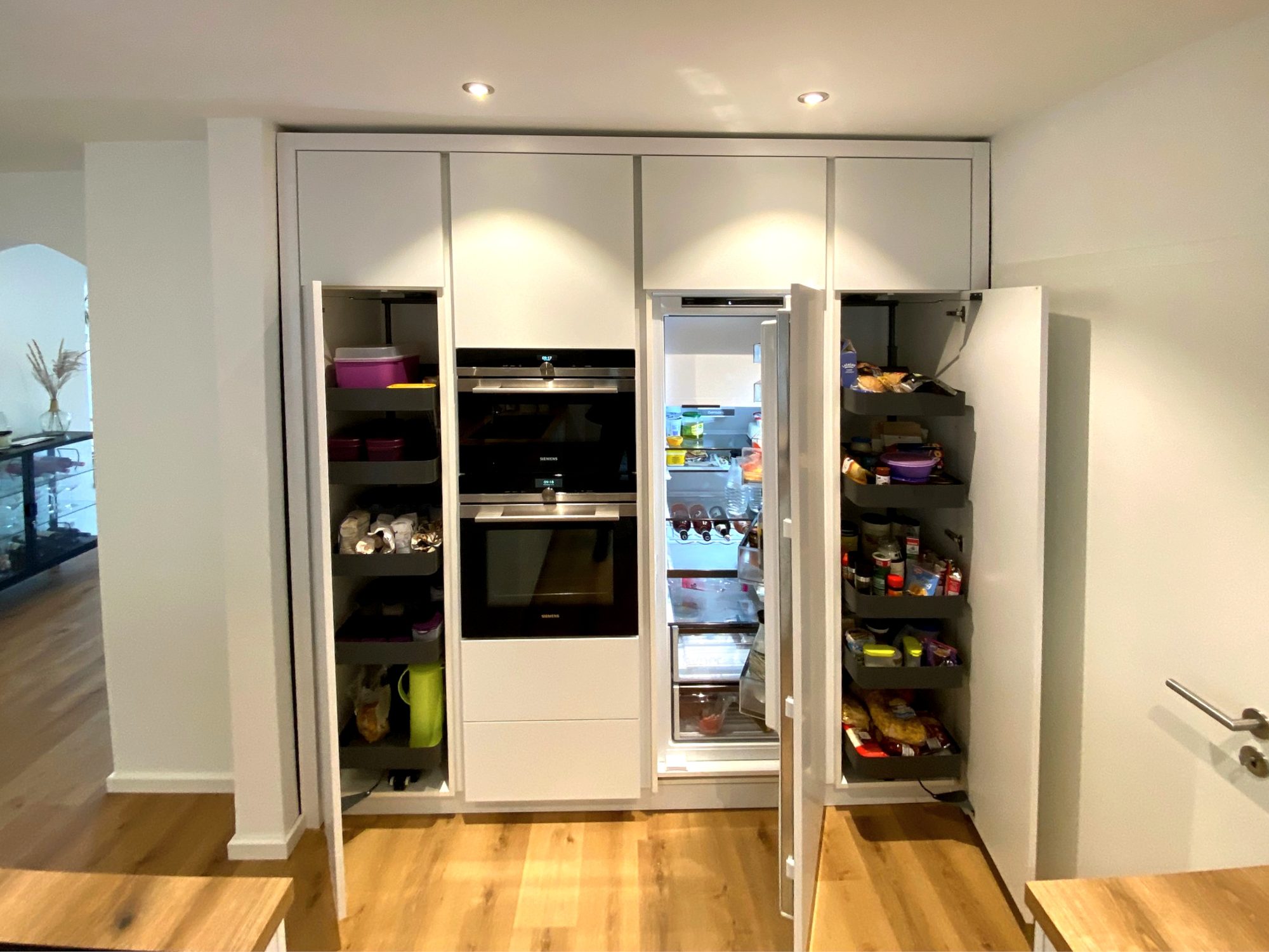 Hochschrankwand mit geöffneten Vorratsauszügen und Kühlschrank