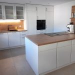 Weiße Landhausküche mit Theke und Glasvitrinen