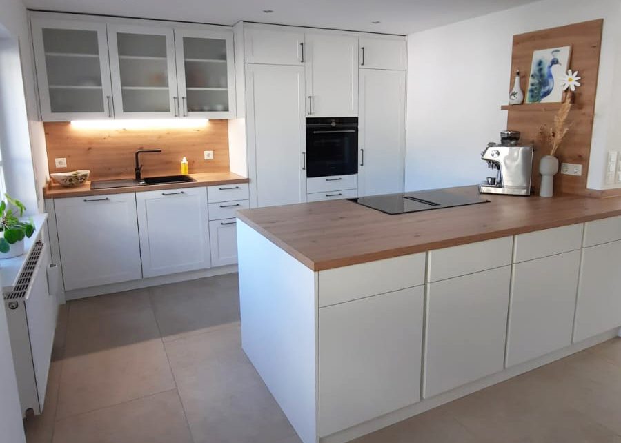 Weiße Landhausküche mit Theke und Glasvitrinen