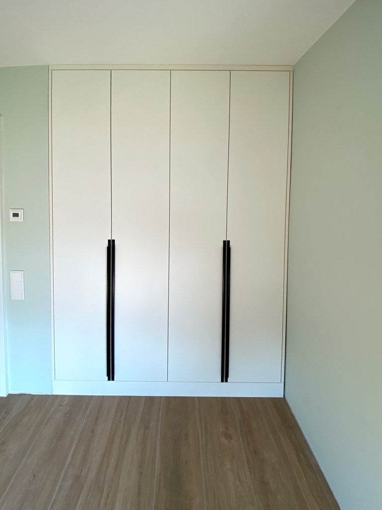 Weißer Einbauschrank mit langen schwarzen Griffen