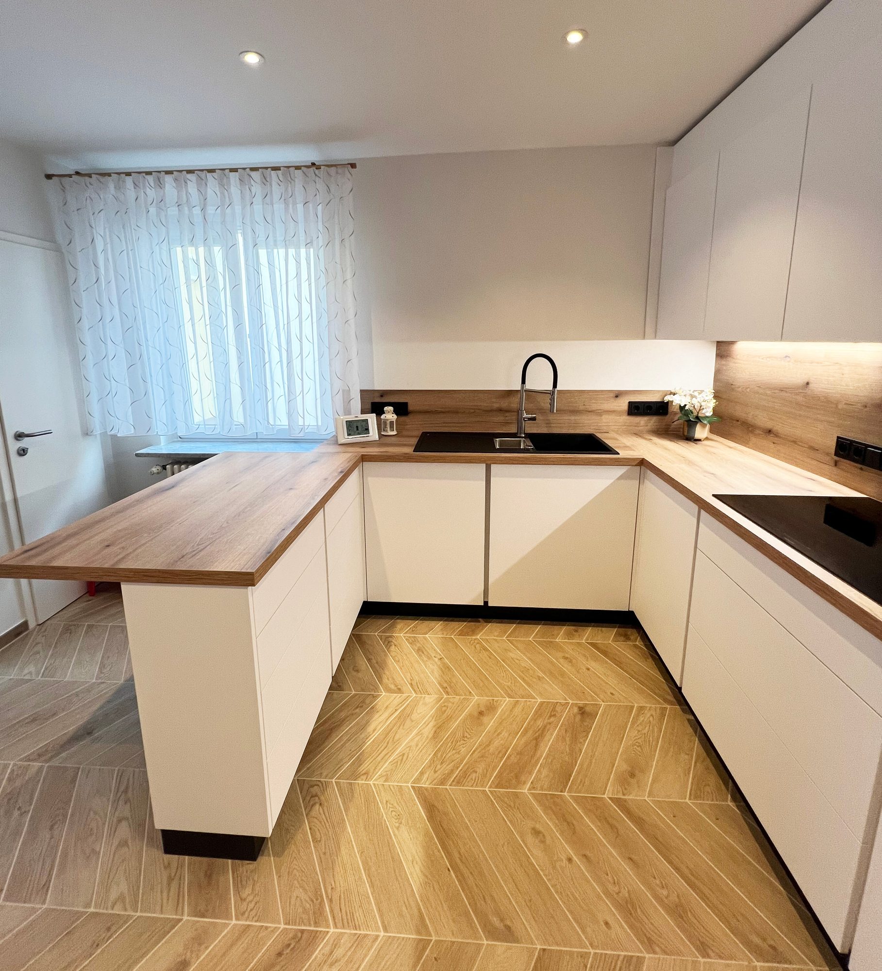 Weiße Küche mit Theke und beleuchteter Rückwand