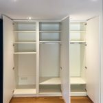 Geöffneter Einbauschrank mit Fachböden und Kleiderstangen