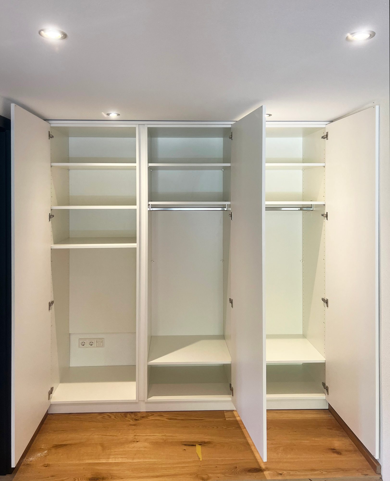Geöffneter Einbauschrank mit Fachböden und Kleiderstangen